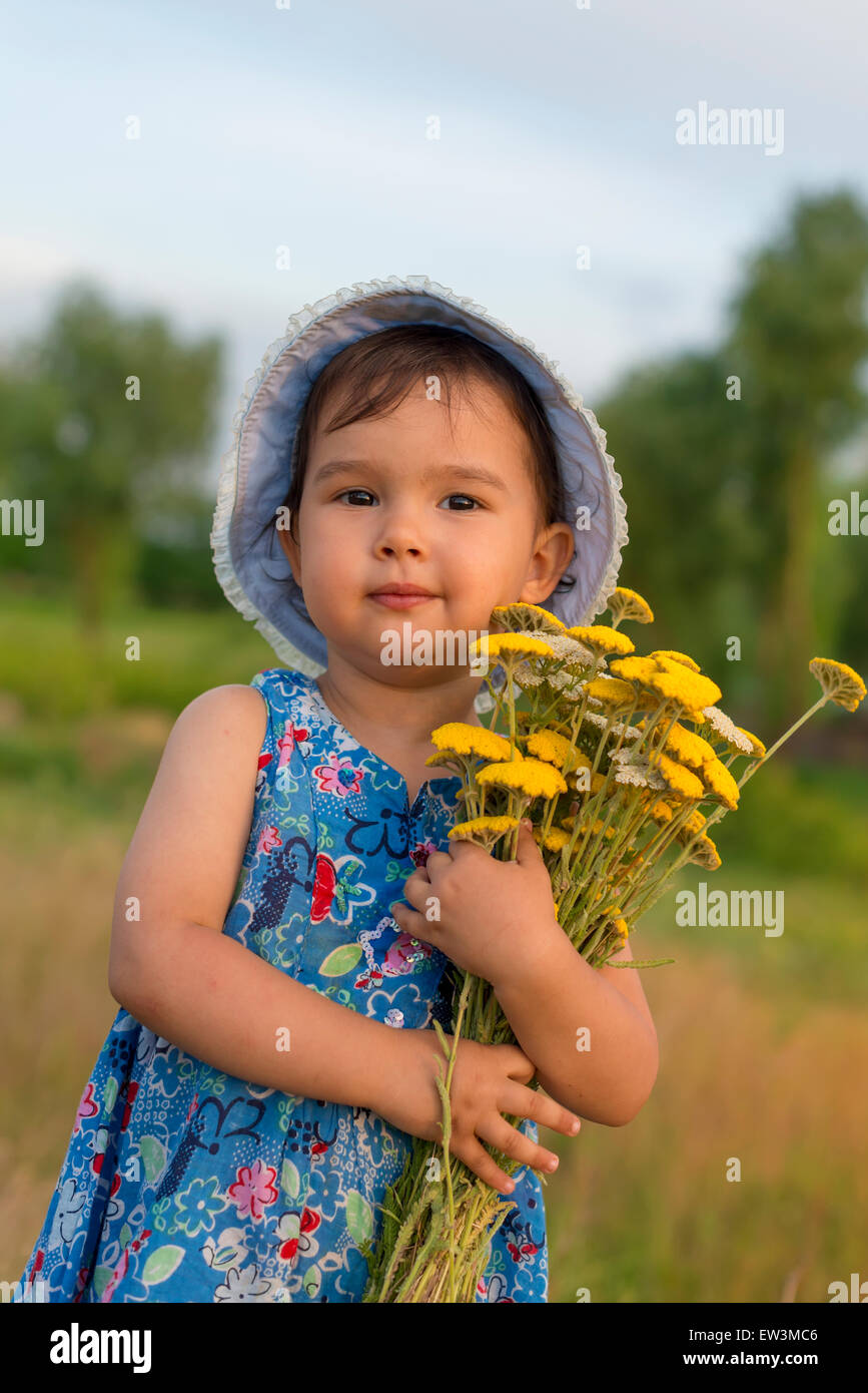 Niedliche kleine Mädchen hält einen Eimer mit Schafgarbe Blumen Stockfoto