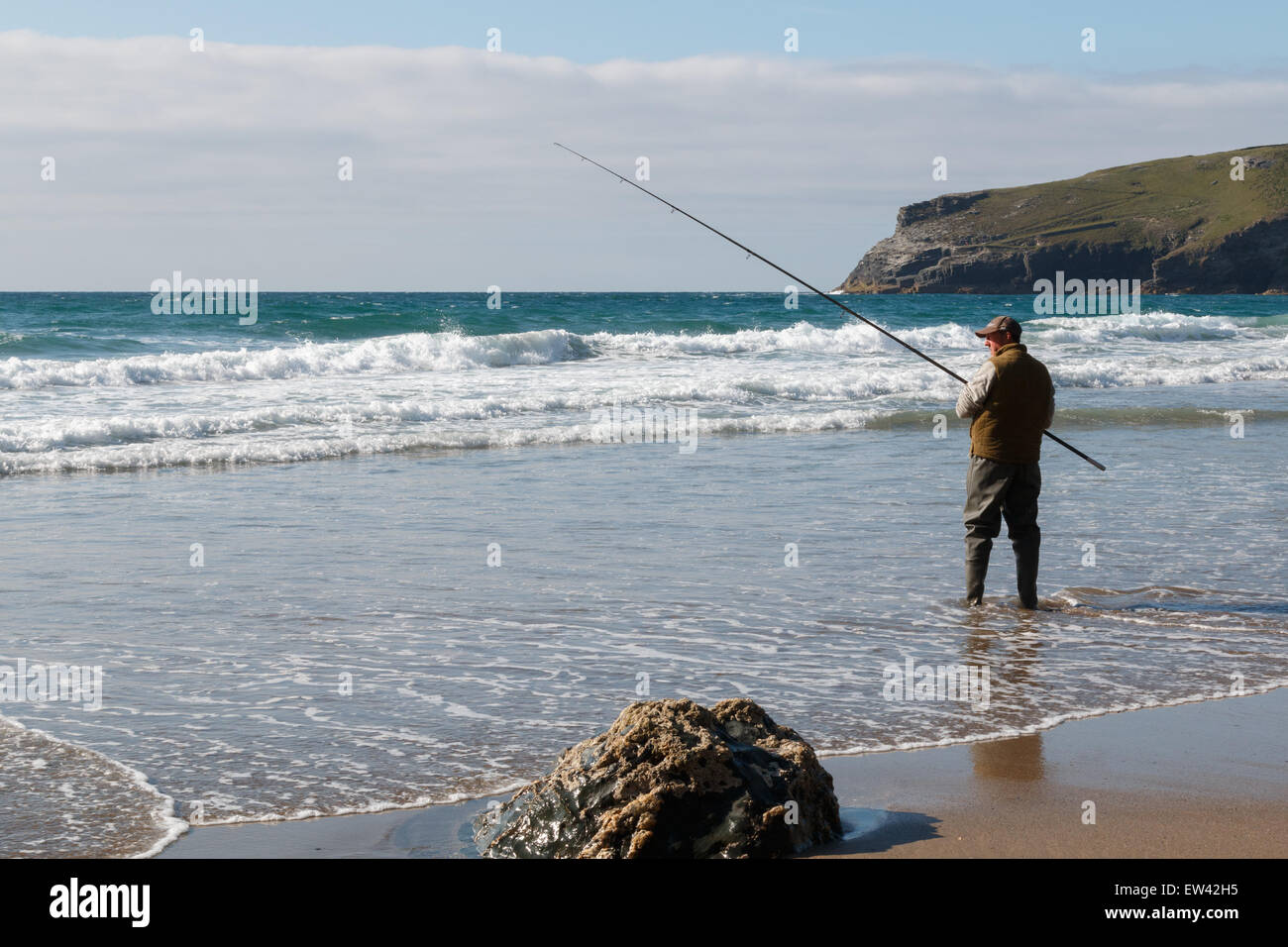 Angler Angeln im Meer. Ein Mann stand am Strand Angeln an der Atlantik Küste bei Trebarwith Strand, Cornwall, UK. Er steht im Meer. Stockfoto