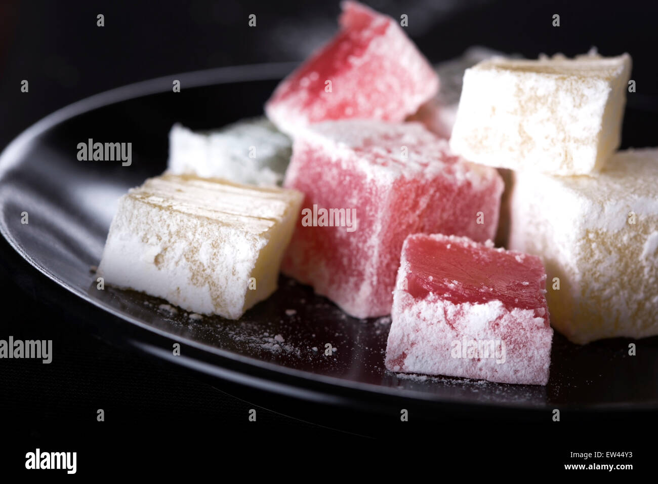 Turkish Delight Stücke auf dunklen Teller auf schwarzem Hintergrund Stockfoto