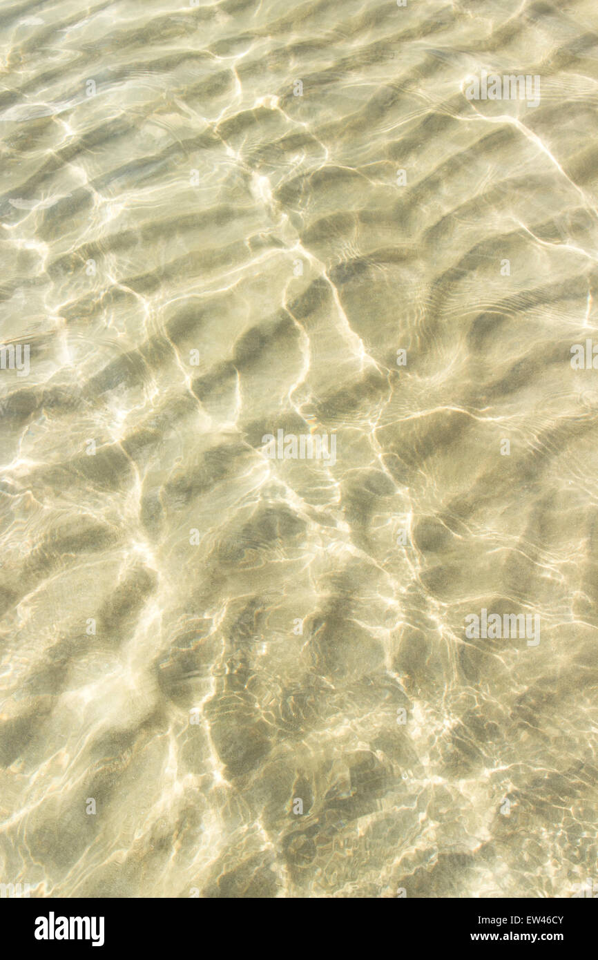 transparentes Wasser plätschern, Sand Wellen und Sonnenlicht blendet. Meer-Tiefpunkt-Muster Stockfoto