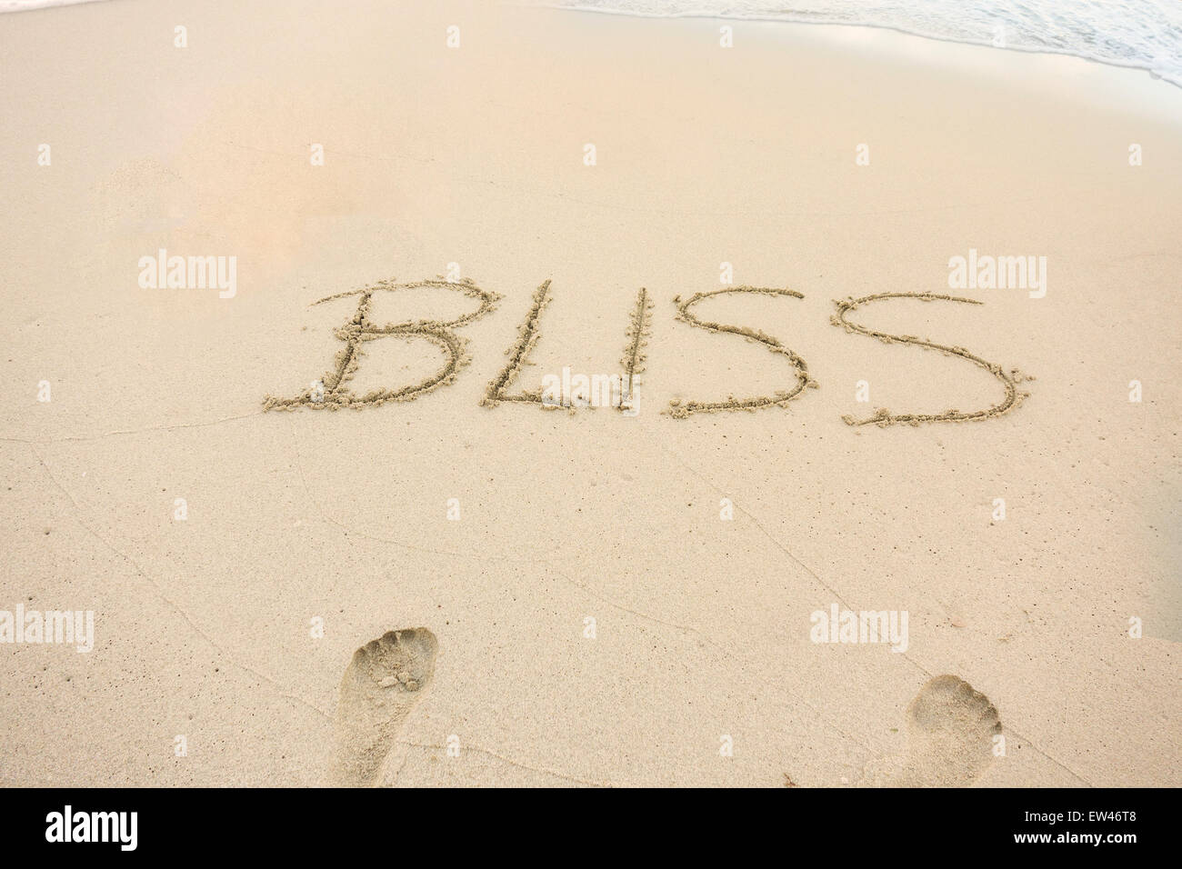 Eine Nachricht, Bliss, geschrieben in den Sand am Strand einer tropischen Insel. Konzeptionelle. Stockfoto