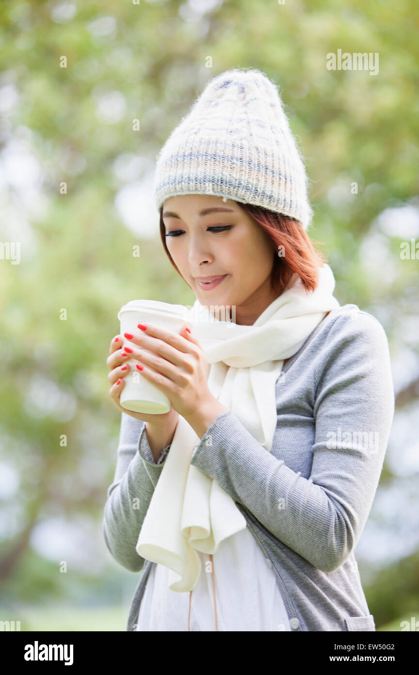 Junge Frau hält einen Drink und Blick nach unten Stockfoto