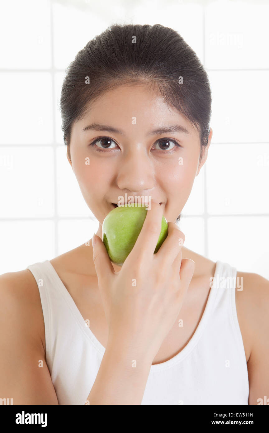 Junge Frau hält einen Apfel und lächelt in die Kamera Stockfoto