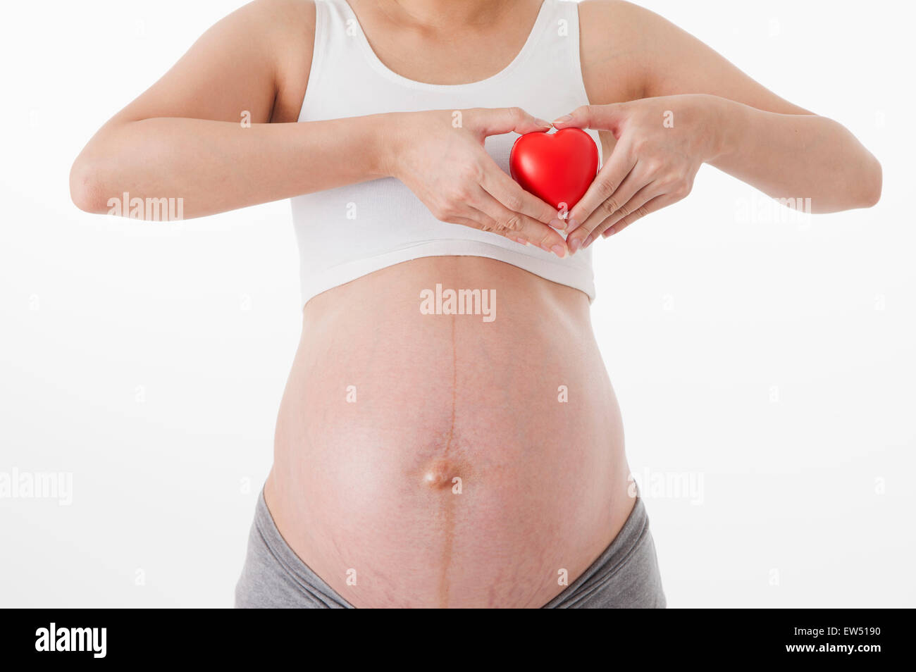 Schwangere Frau mit Herzform gestikulieren, Stockfoto