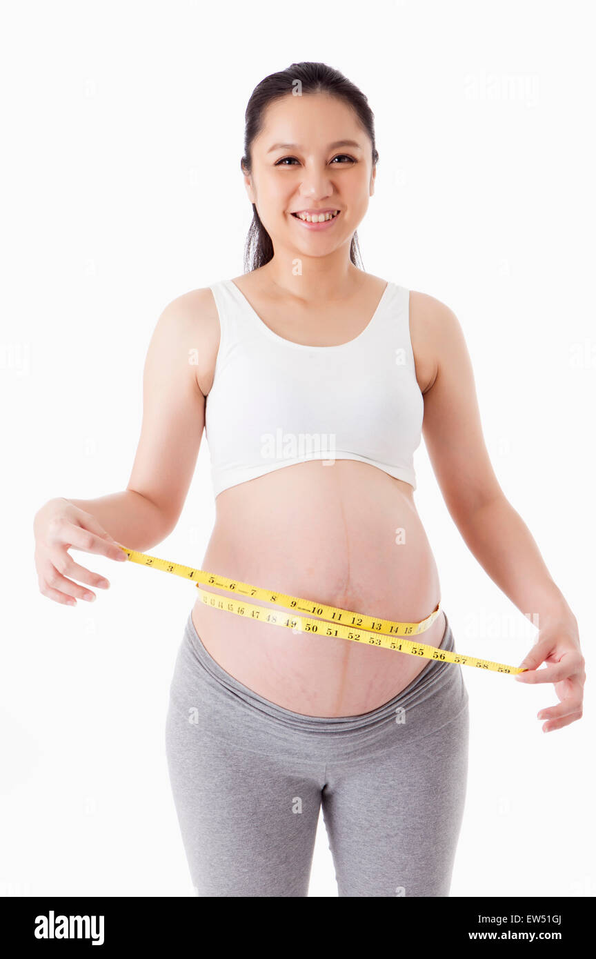 Schwangere Frau mit Maßnahme Band und lächelt in die Kamera Stockfoto