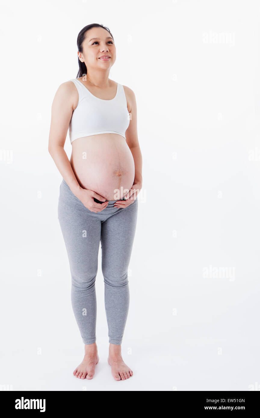 Schwangere Frau stehen und blickte mit Lächeln, Stockfoto