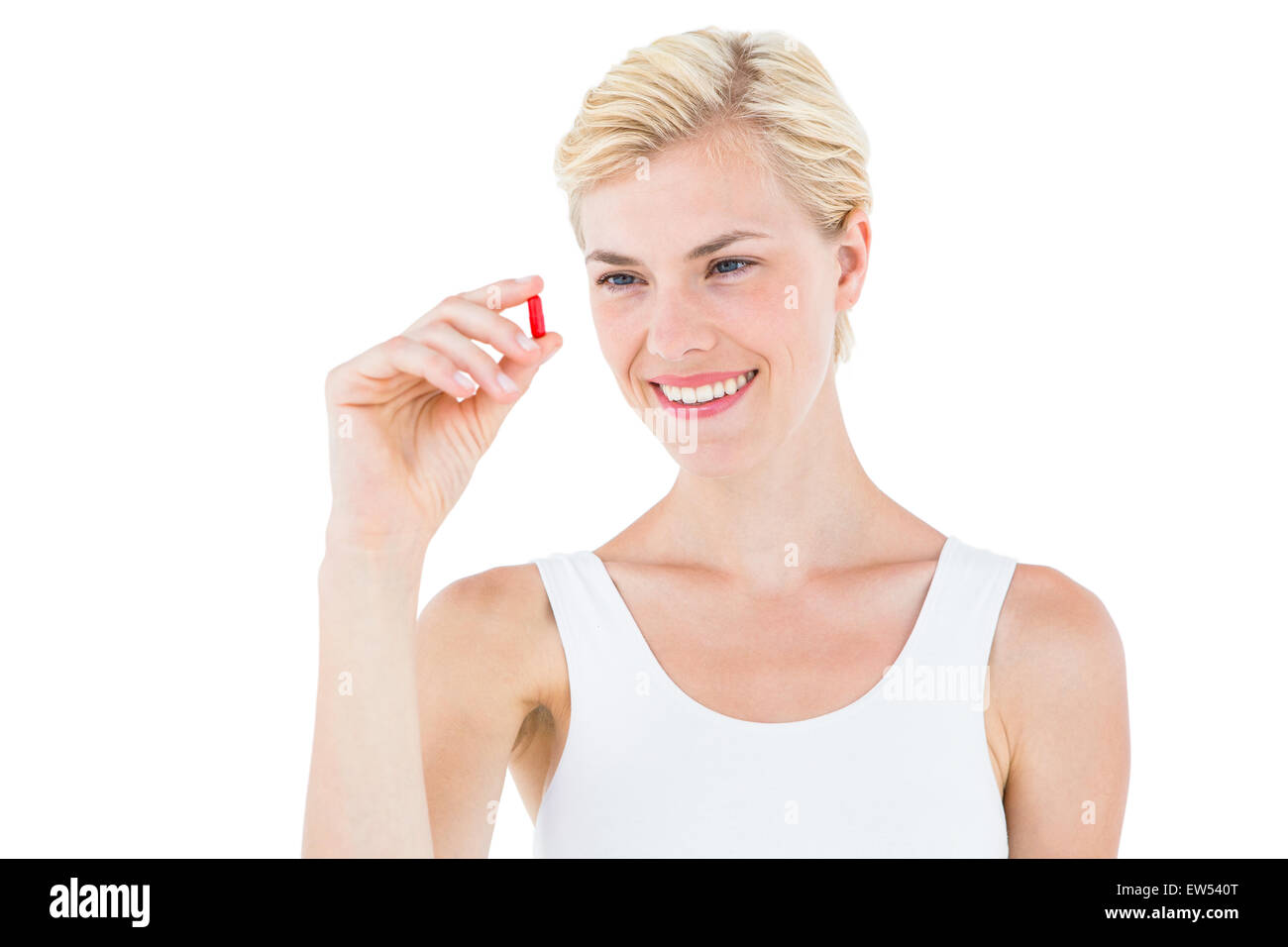 Lächelnde blonde Frau, die rote Pille betrachten Stockfoto