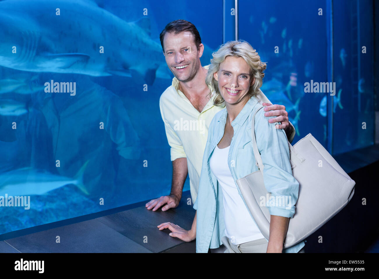 Glückliches Paar Blick in die Kamera neben dem Aquarium Stockfoto