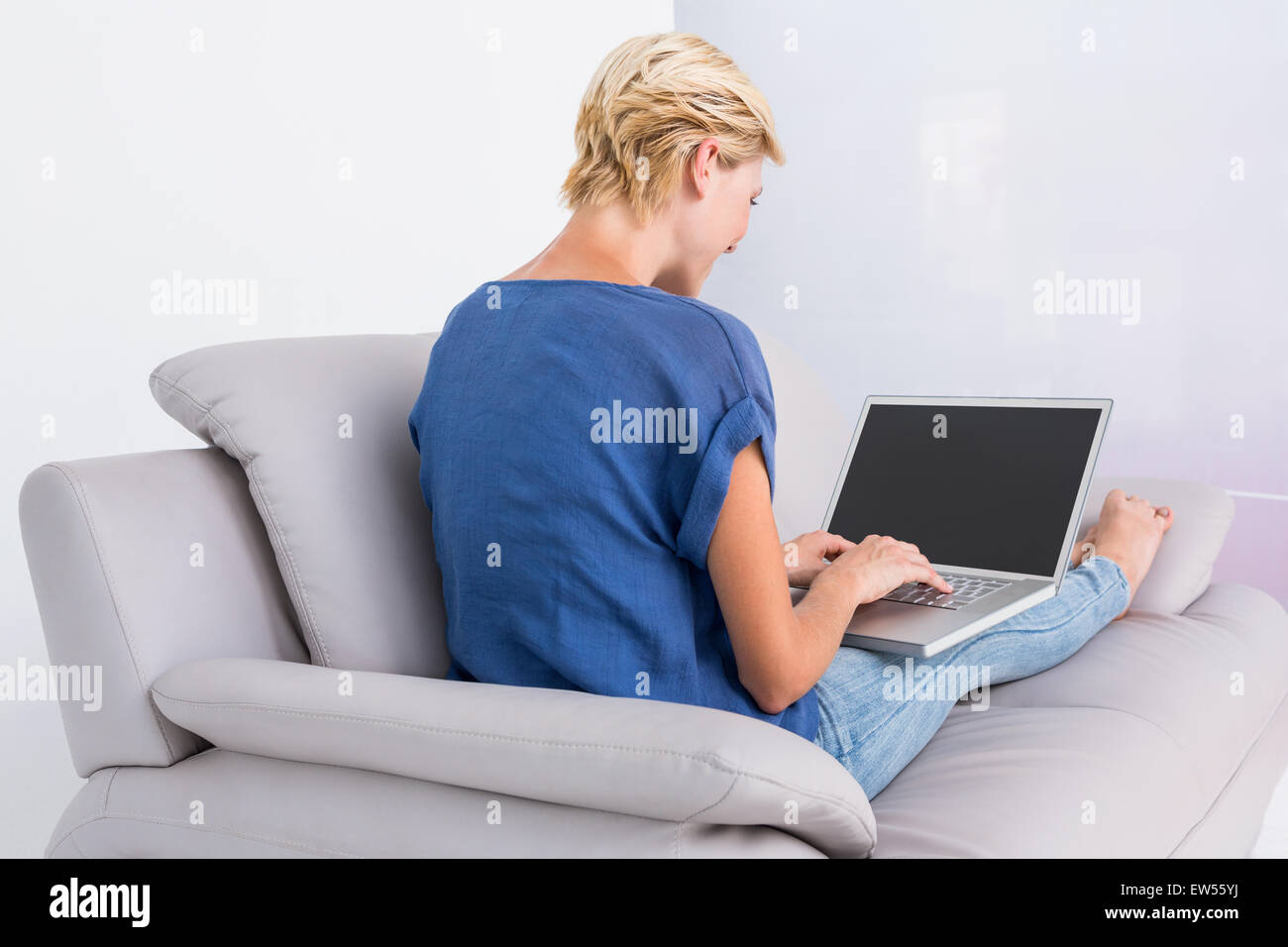 Blonde Frau mit ihrem Laptop auf der couch Stockfoto