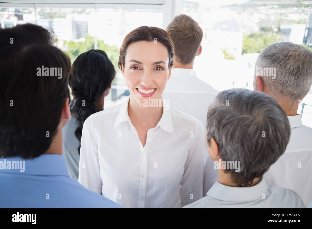 Lächelnd Geschäftsfrau mit Kollegen zurück zu Kamera Stockfoto