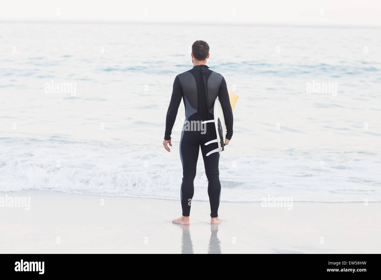 Mann im Anzug mit einem Surfbrett an einem sonnigen Tag Stockfoto