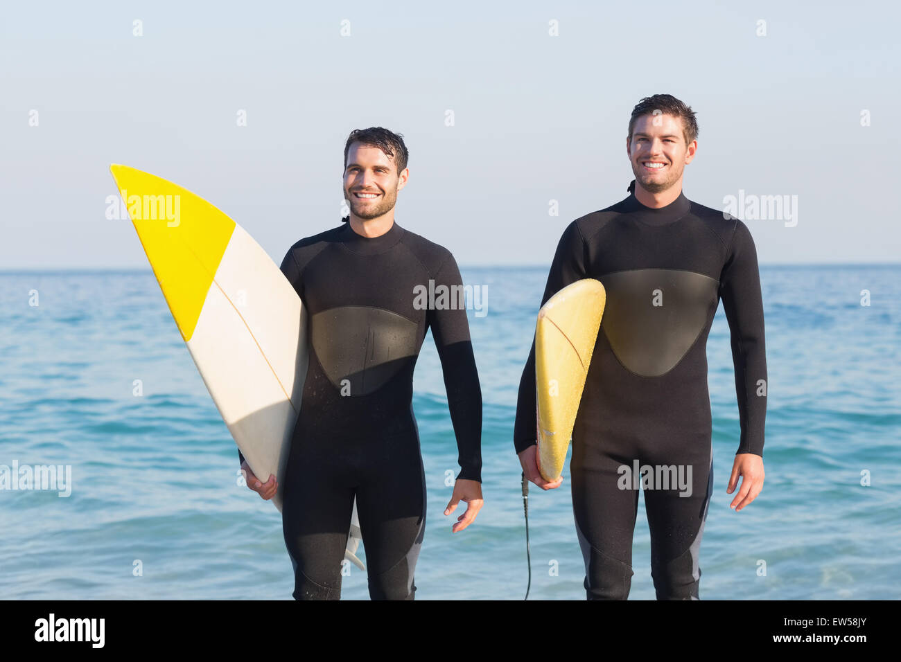 Zwei Männer in Anzügen mit einem Surfbrett an einem sonnigen Tag Stockfoto