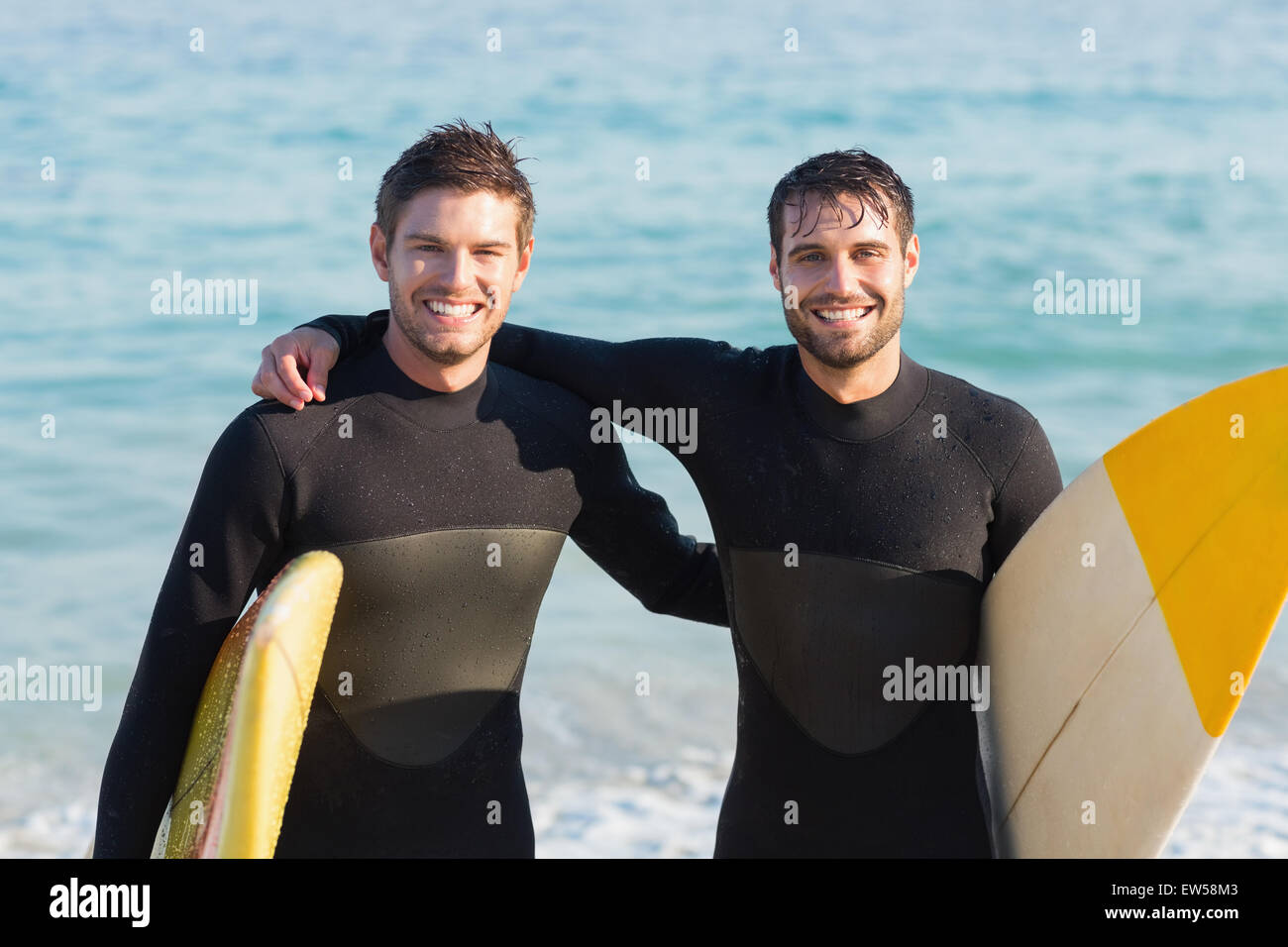 Zwei Männer in Anzügen mit einem Surfbrett an einem sonnigen Tag Stockfoto