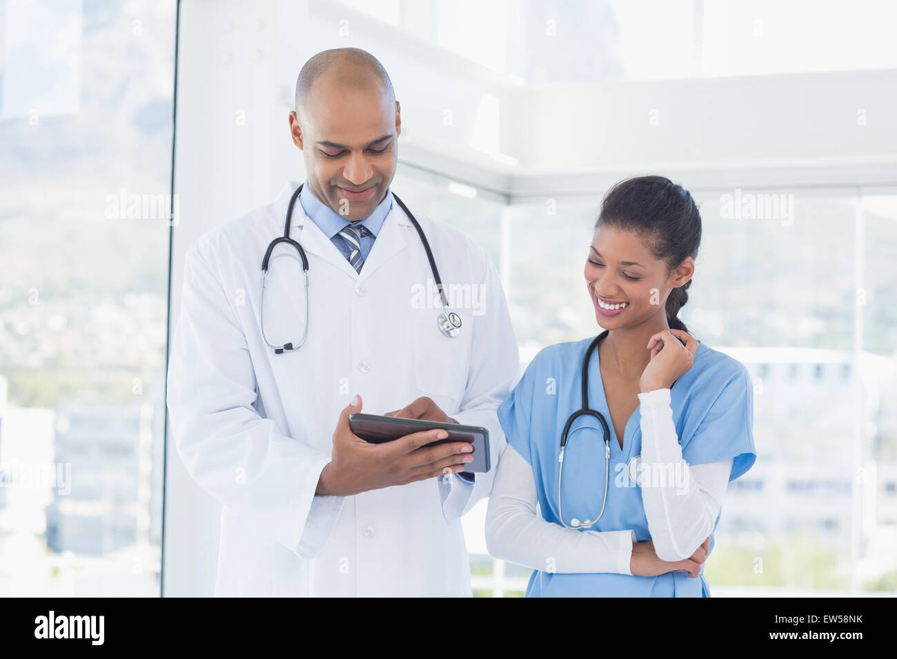 Lächelnde Ärzte arbeiten zusammen mit tablet Stockfoto