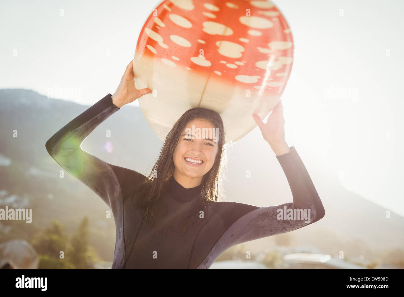 Frau im Neoprenanzug mit einem Surfbrett an einem sonnigen Tag Stockfoto