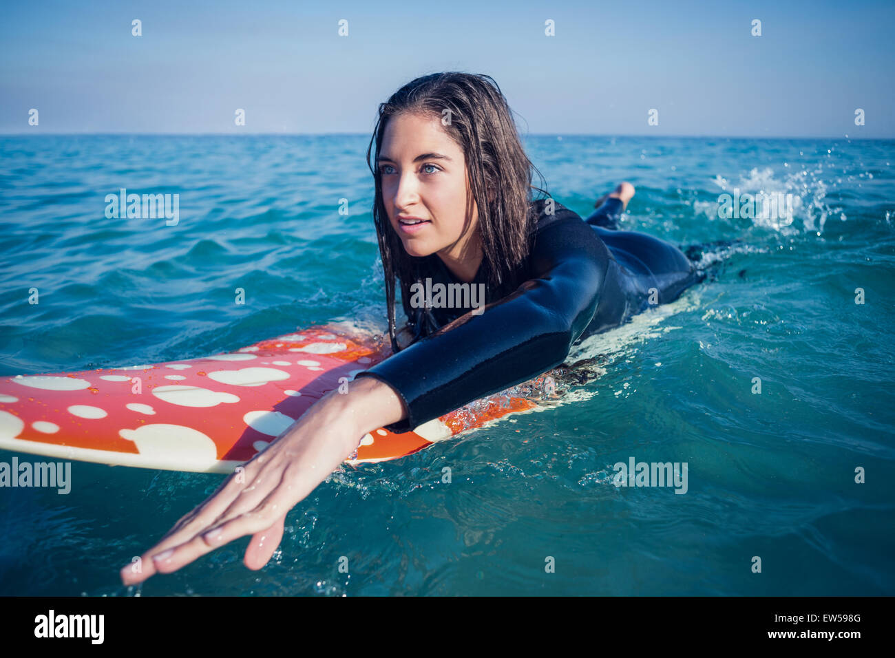 Frau im Neoprenanzug mit einem Surfbrett an einem sonnigen Tag Stockfoto