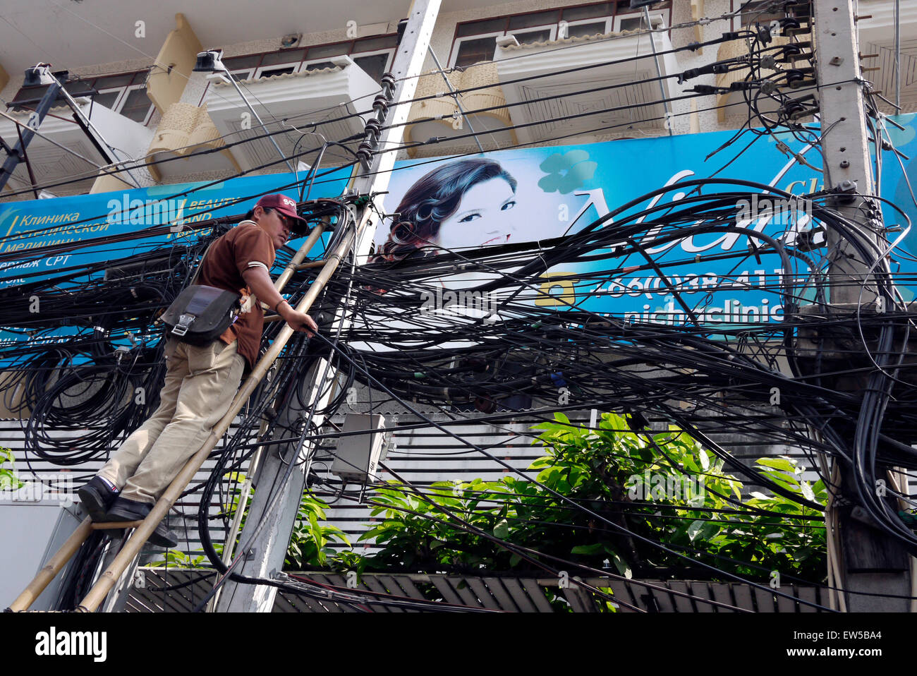 Elektrische Kabel Monteur in einer gefährlichen Situation über einer Stadt Straße in Pattaya Thailand arbeiten Stockfoto