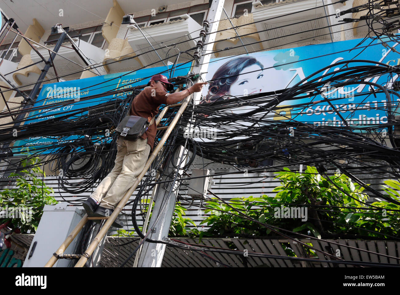 Elektrische Kabel Monteur in einer gefährlichen Situation über einer Stadt Straße in Pattaya Thailand arbeiten Stockfoto