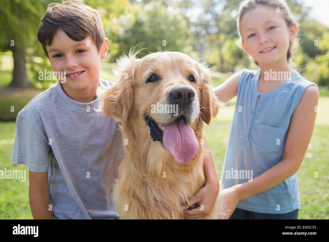 Lächelnde Geschwister mit ihrem Hund im park Stockfoto