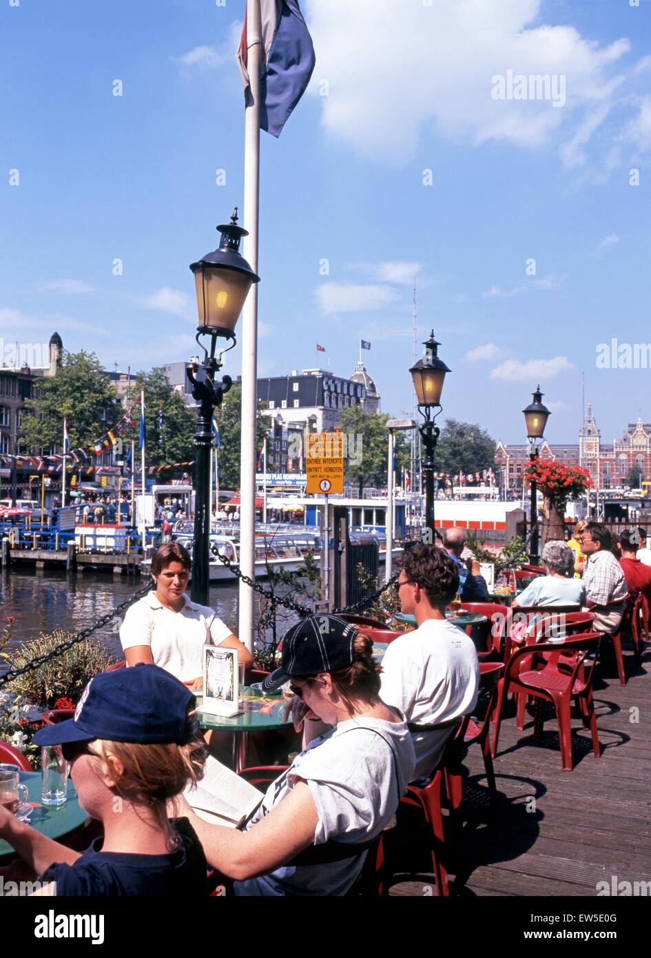 Menschen entspannen in einem Straßencafé entlang Damrak, Amsterdam, Holland, Niederlande, Europa. Stockfoto