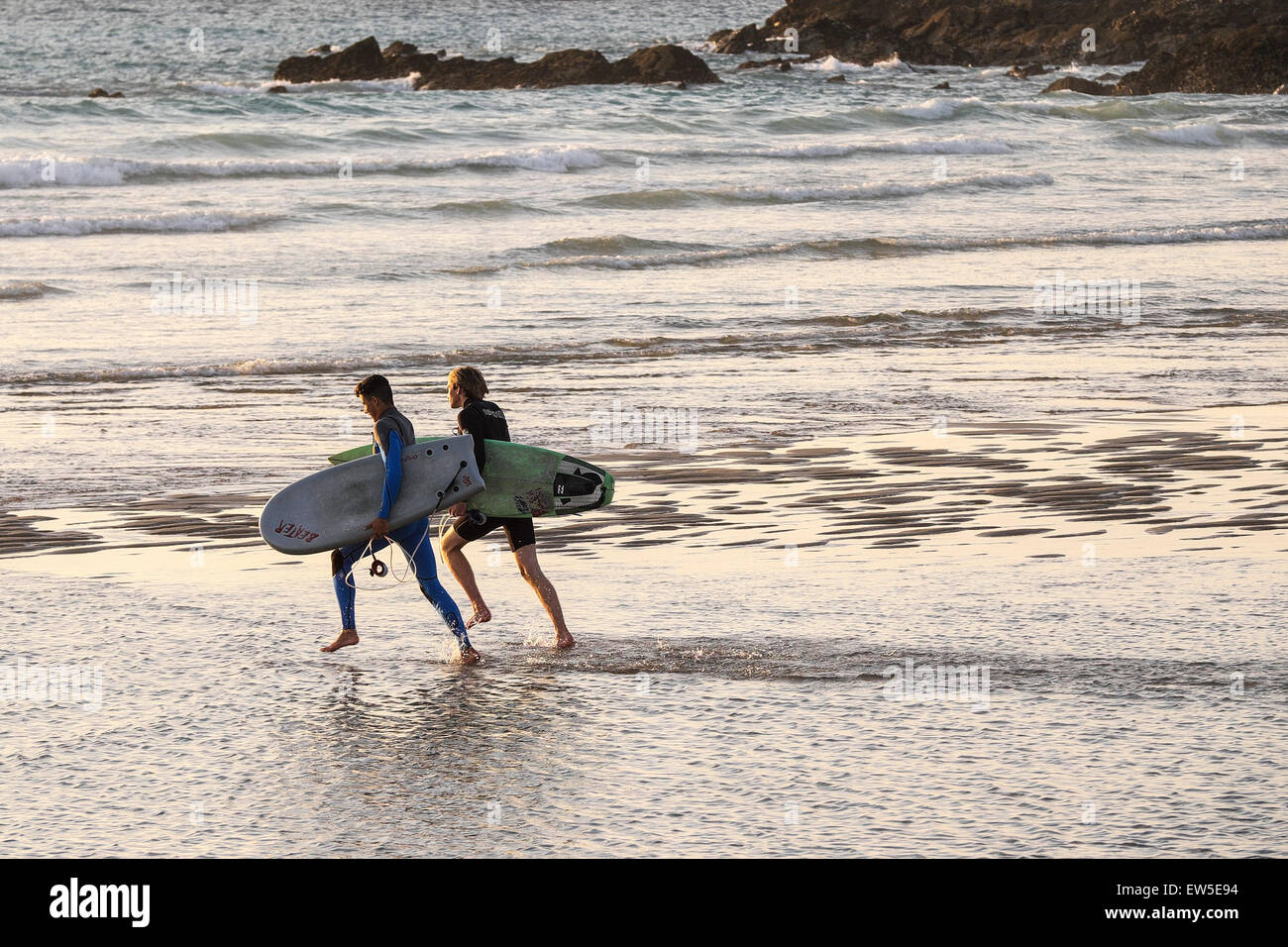Zwei Surfer am Fistral Strand in Newquay, Cornwall ins Meer laufen. VEREINIGTES KÖNIGREICH. Stockfoto