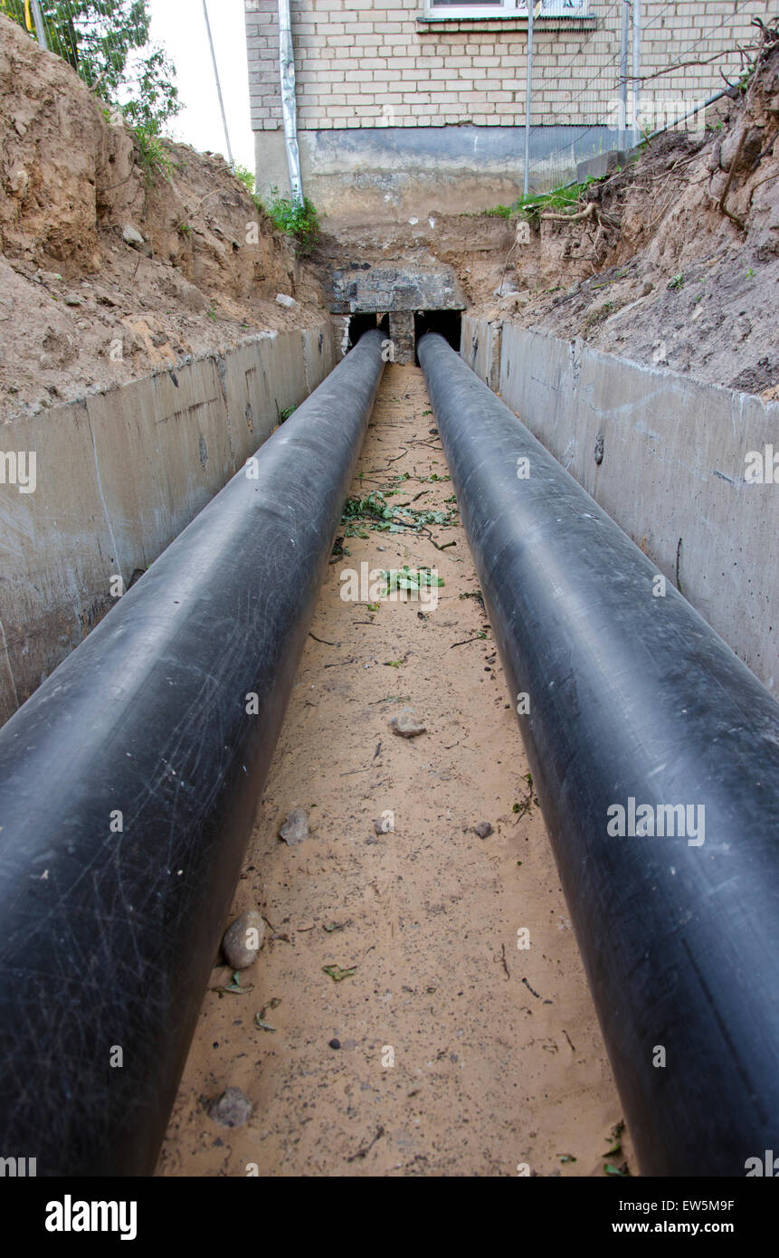 neue moderne Kunststofftechnik schwarz Heizungsrohre im Graben in der Nähe von Stadthaus Stockfoto