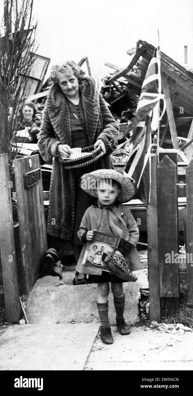 Während des zweiten Weltkrieges steht ein kleiner Junge vor den Trümmern seines ausgebombten Hauses. In seinen Händen, ein Foto von der königlichen Familie. Liverpool, ca. 1941. Stockfoto