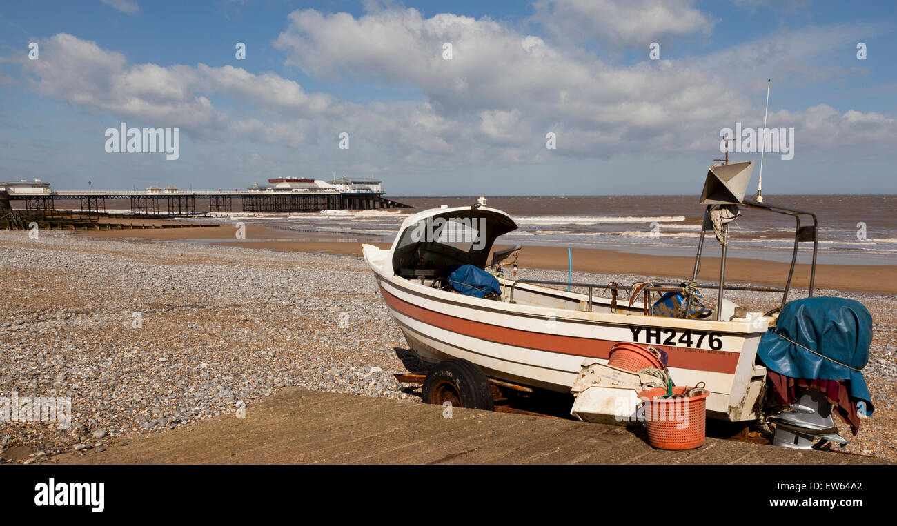 Ein Fischerboot am Cromer Beach, Norfolk, England, UK, mit dem Meer und Pier im Hintergrund Stockfoto