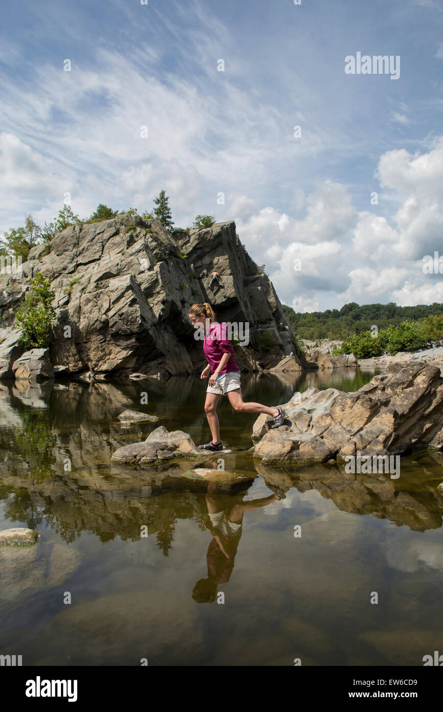 Eine Frau Wanderungen und Felsen klettert auf dem Billy Goat Trail in Great Falls National Park, MD als Mann klettert Felsen in der Ferne Stockfoto