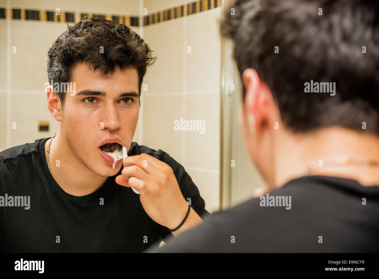 Kopfschuss attraktive junge Mann Zähneputzen mit Zahnbürste, selbst im Spiegel betrachten Stockfoto