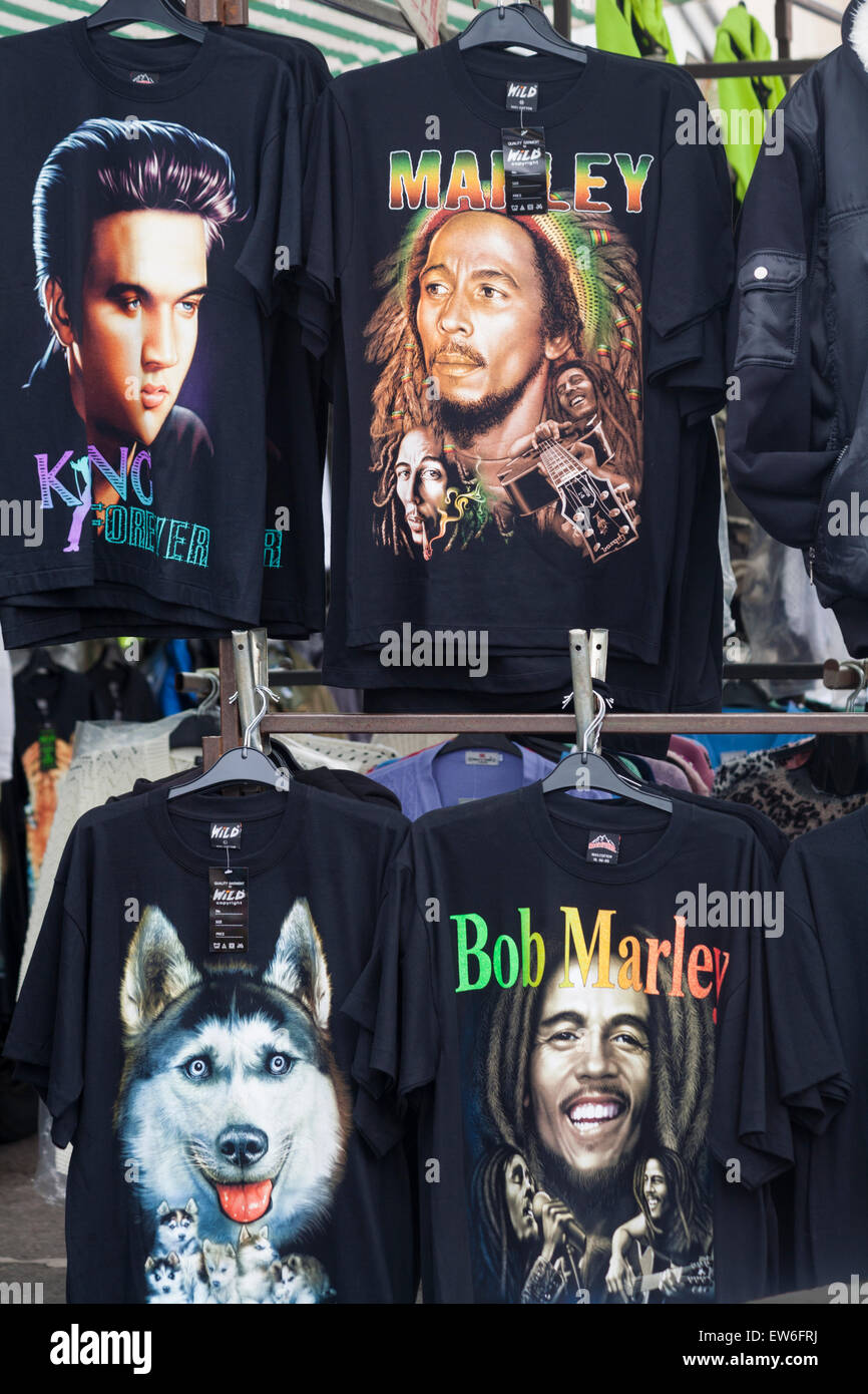 t-Shirts zum Verkauf am Marktstand, darunter Bob Marley und Elvis Presley in Dorchester, Dorset, Großbritannien im Juni - T-Shirts, T-Shirts, T-Shirts Stockfoto