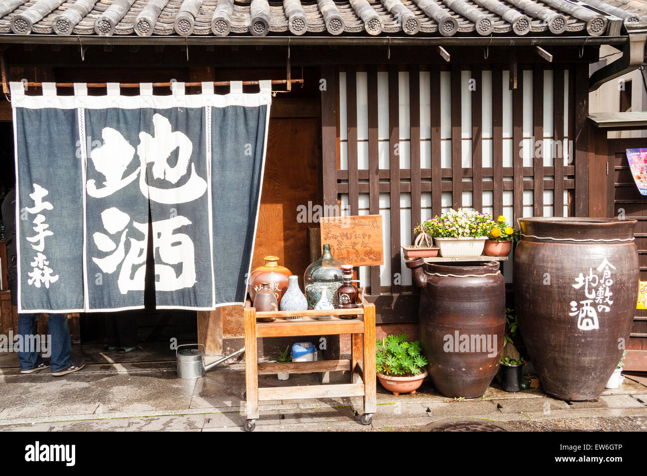 Kurashiki. Bikan-Historisches Gebiet. Traditionelles japanisches gasthaus,  Ryokan. Lange Noren-Vorhänge hängen über der Tür. Alte Flaschen draußen auf  kleinem Tisch Stockfotografie - Alamy