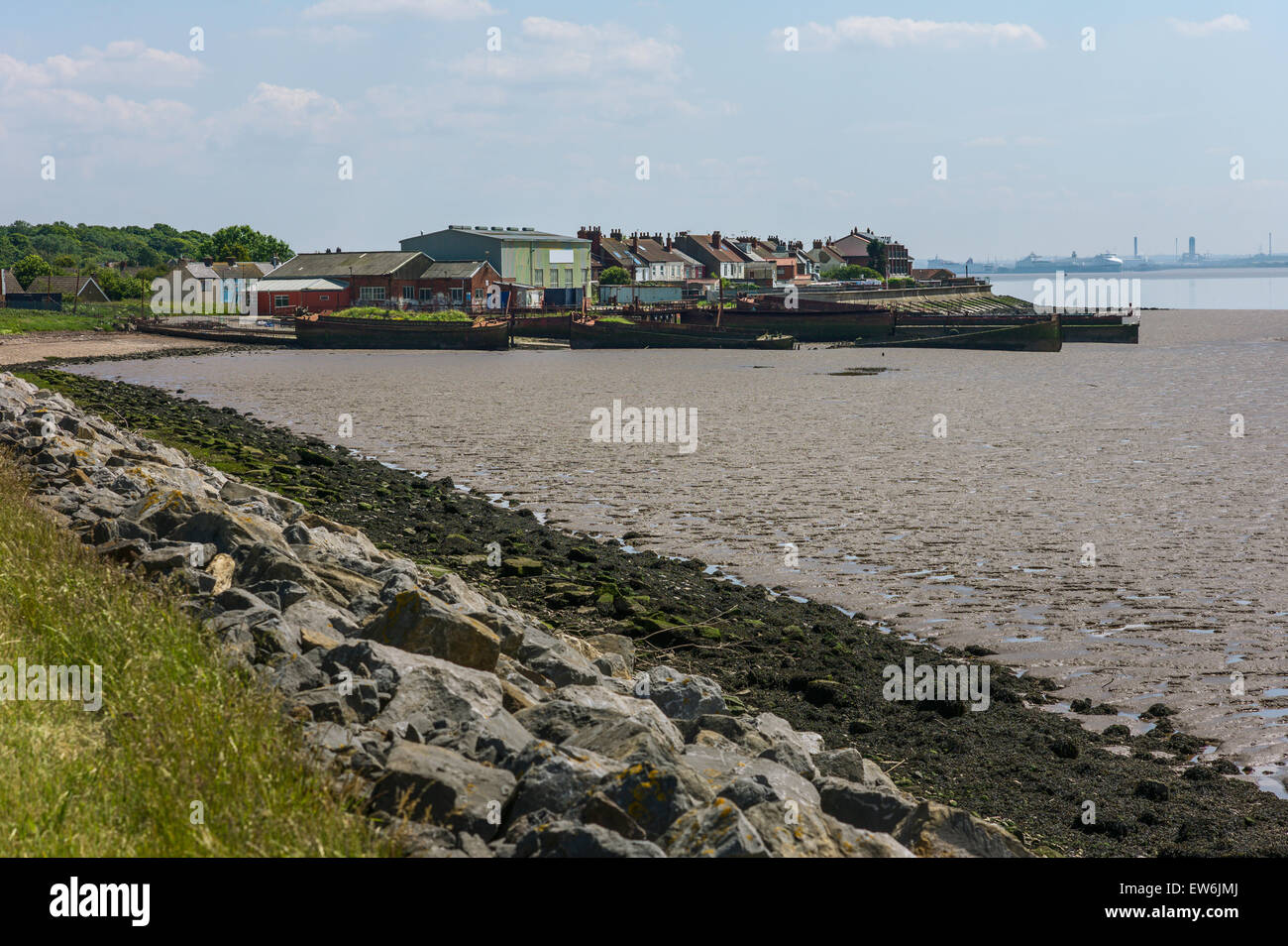 Blick über die Mudbanks der Mündung des Humber bei Ebbe auf einer stillgelegten Werft, verlassene Schiffe und das Dorf Paull Stockfoto