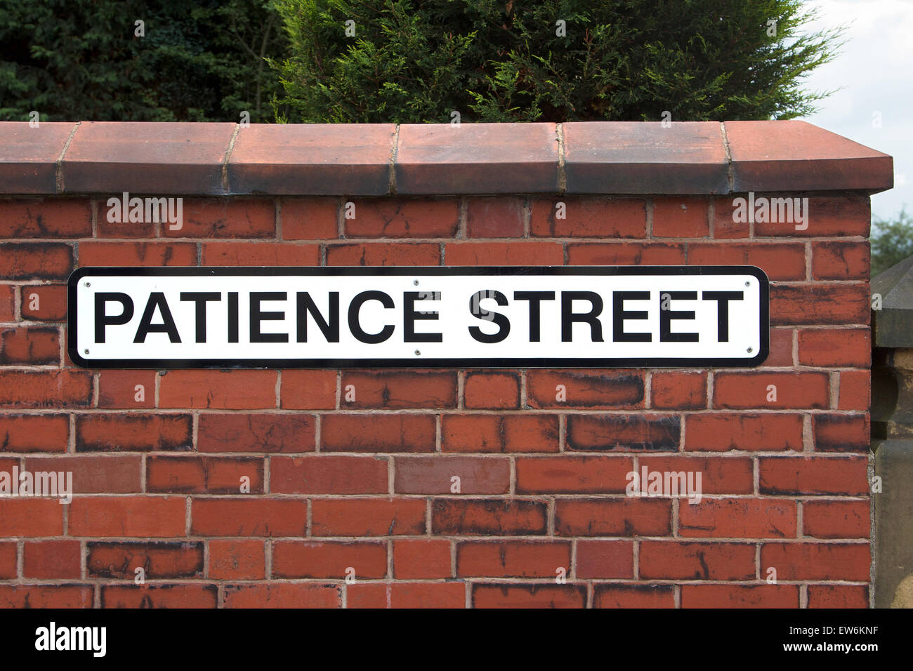 "Geduld" Straßenschild auf roten Backsteinmauer Stockfoto