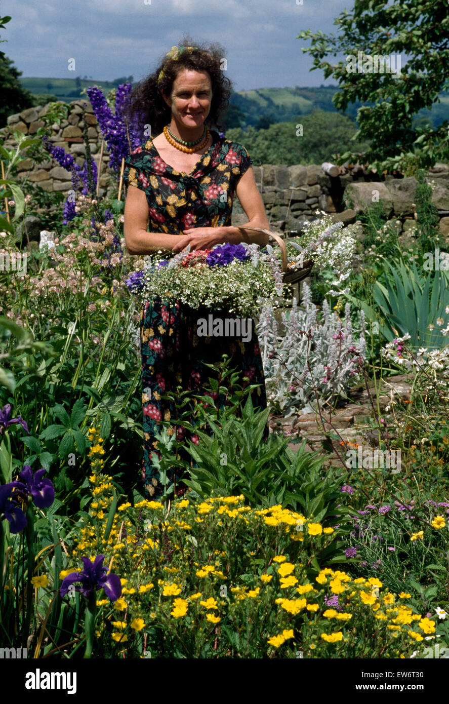 Porträt einer Frau mit einem Korb von Schnittblumen in einem Landschaftsgarten Stockfoto