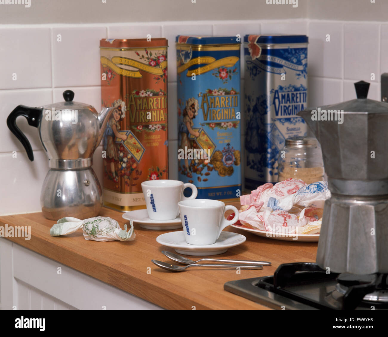 Espresso Kaffee Töpfe und Dosen von Amaretti-Keksen auf Arbeitsplatte mit Milchkaffee Tassen Stockfoto