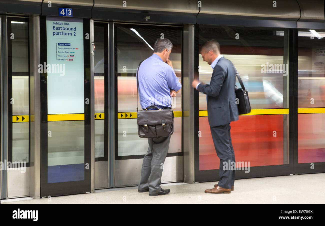 Zwei Geschäftsleute warten auf ein Rohr zu trainieren, auf einer Plattform von einer u-Bahn-Station der Jubilee Line London Stockfoto