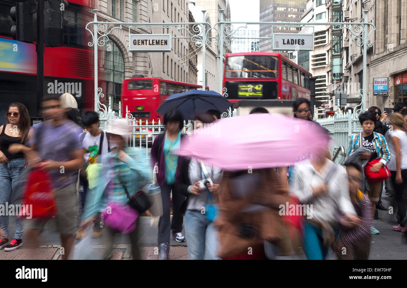 Menschen wandern in den Regen und halten Sonnenschirme in einer belebten Straße in London Stockfoto