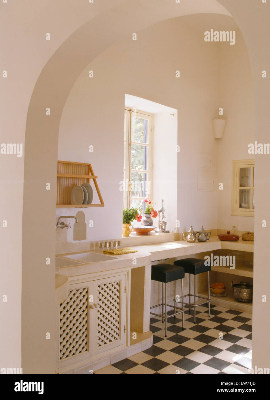 Torbogen zu weißen marokkanische Küche mit schwarz + weiß Schachbrettmuster geflieste Boden Stockfoto