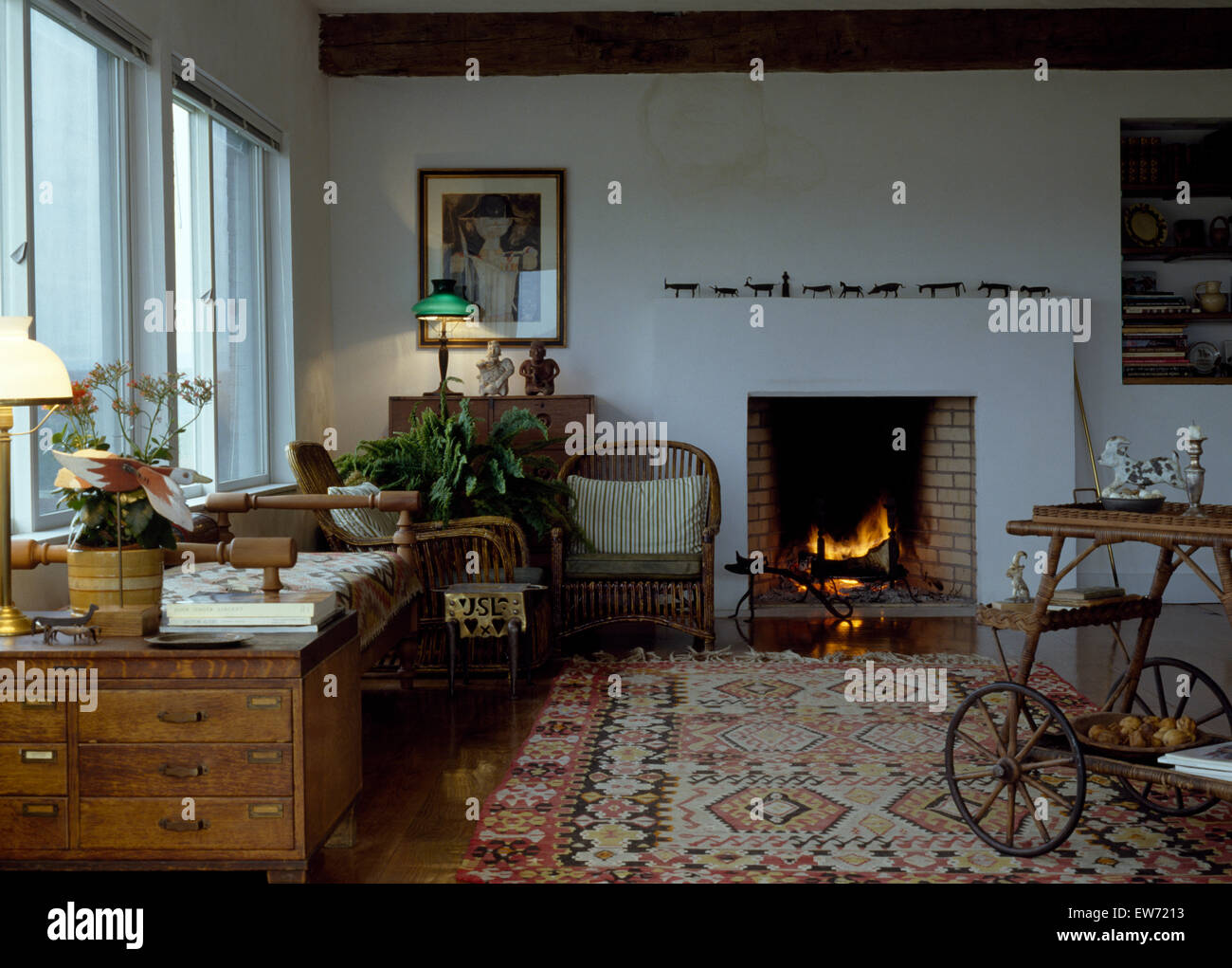 Kelim Teppich und alte Kiefer Truhe im Land Wohnzimmer mit brennenden Feuer im Kamin Stockfoto