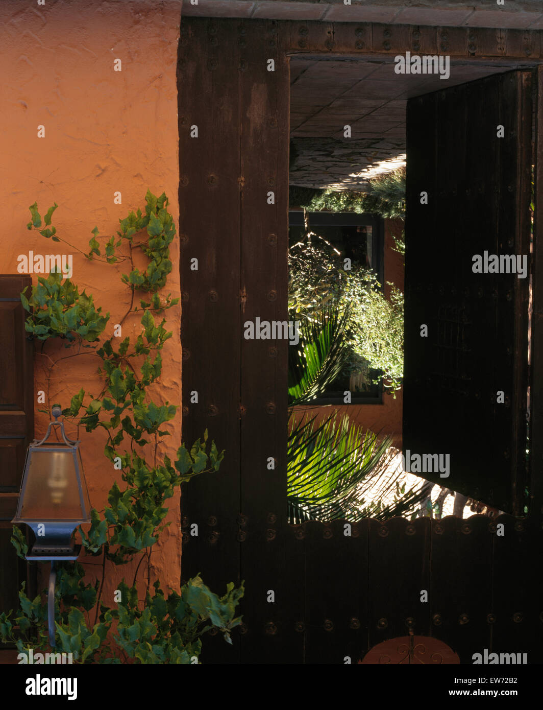 Glas Laterne an der spanische Villa mit Blick durch Holztüren von grünen Pflanzen im Innenhof Stockfoto