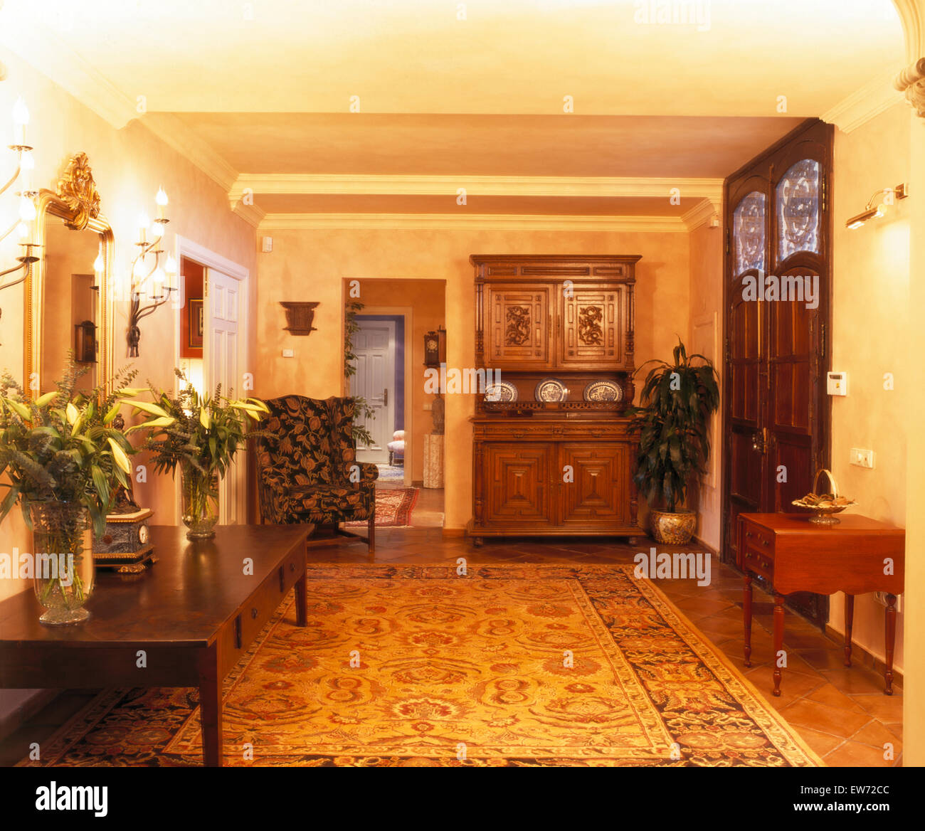 Groß gemusterten Teppich und geschnitzte hölzerne Kommode in Halle mit Vasen mit weißen Lilien auf Konsolentisch in spanischen villa Stockfoto