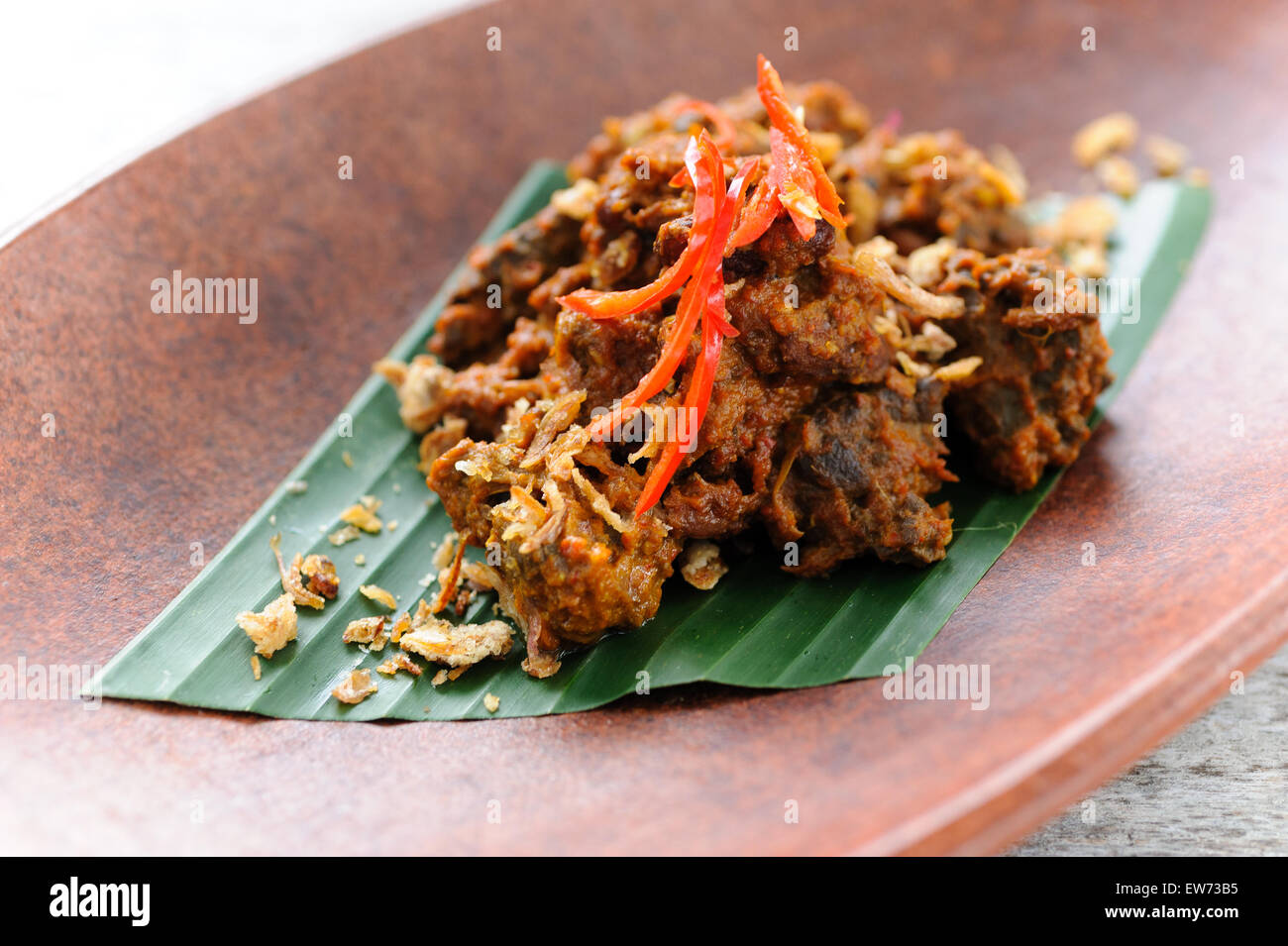 Indonesische Rindfleisch Rendang garniert mit gebratenen Schalotten und rote Chillies. Stockfoto