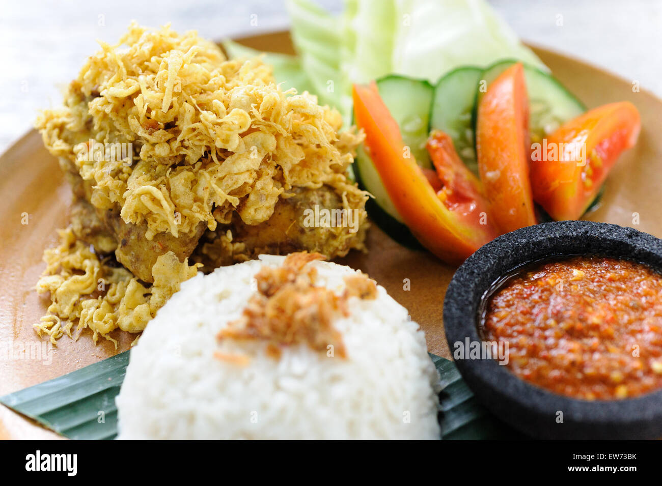 Brathähnchen Indonesisch-Stil, bekannt als Lalapan, serviert mit Reis, Sambal und Gemüse. Stockfoto