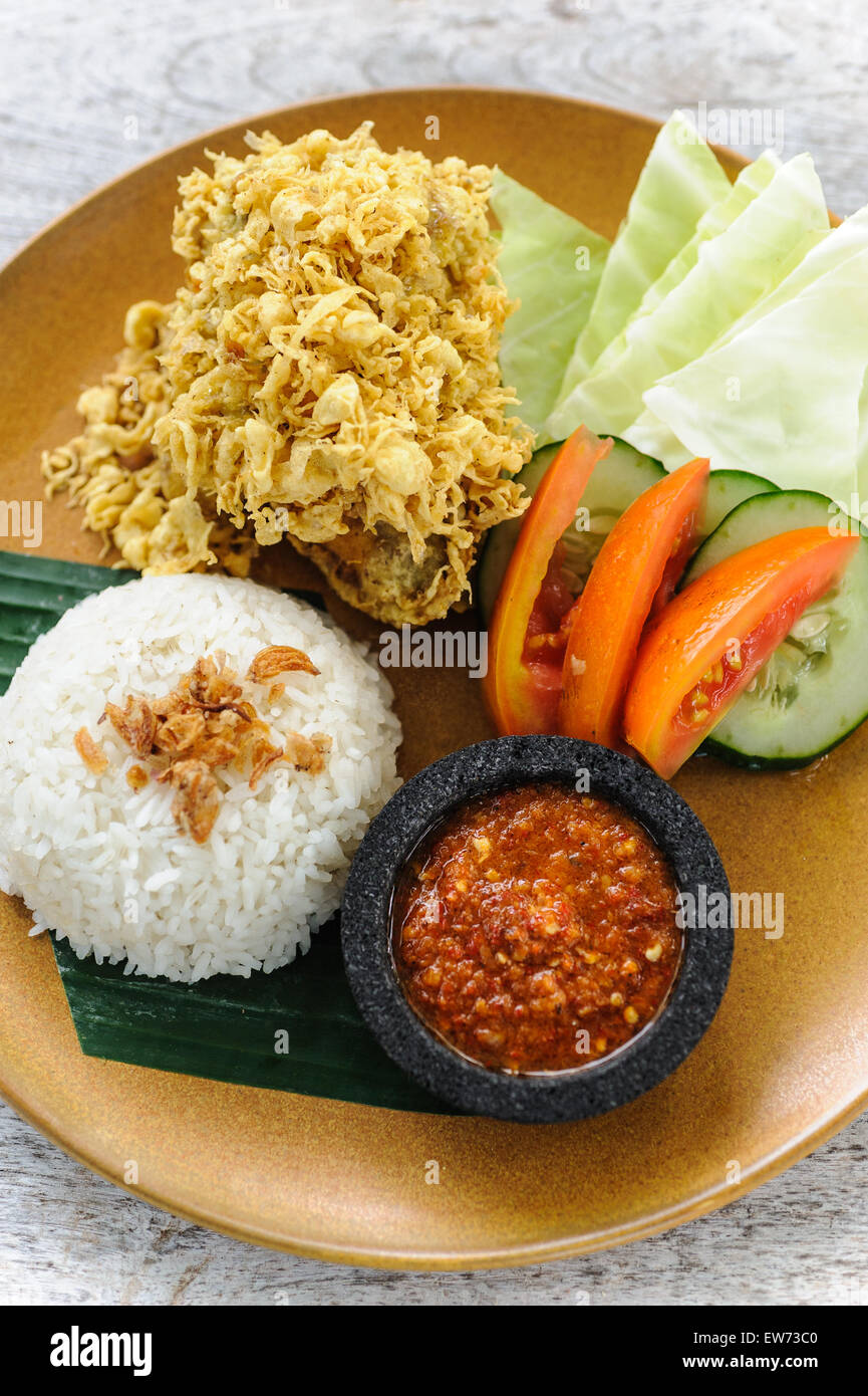 Brathähnchen Indonesisch-Stil, bekannt als Lalapan, serviert mit Reis, Sambal und Gemüse. Stockfoto