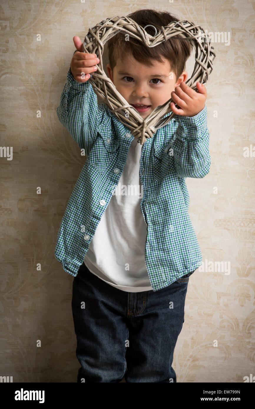 Kleiner Junge mit einem Herz aus Holz in der hand Stockfoto