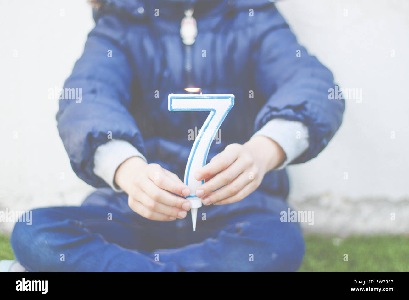 Mädchen sitzen cross legged mit einer Nummer sieben Kerze Stockfoto