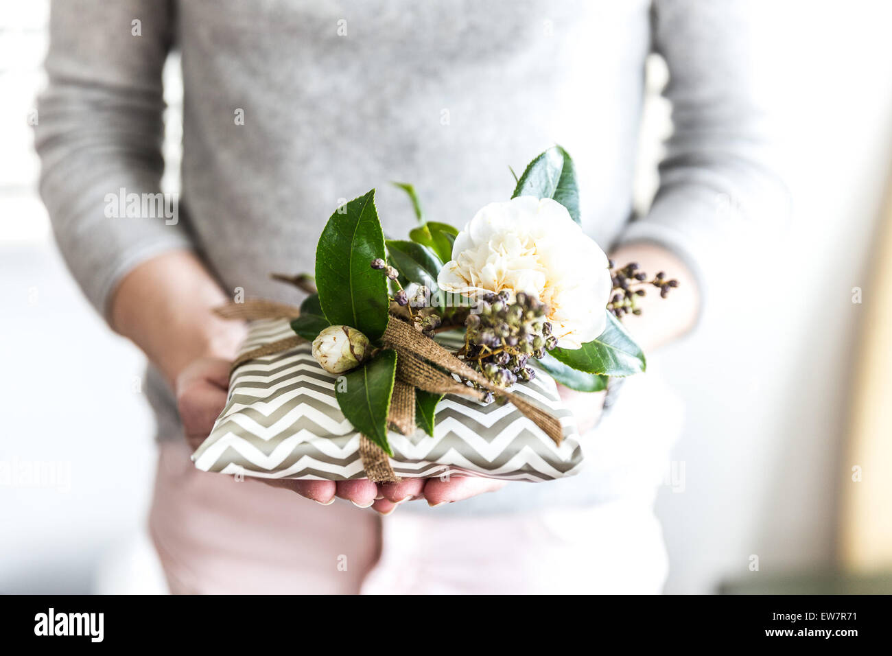 Frau Holding verpacktes Geschenk mit Blumen geschmückt Stockfoto