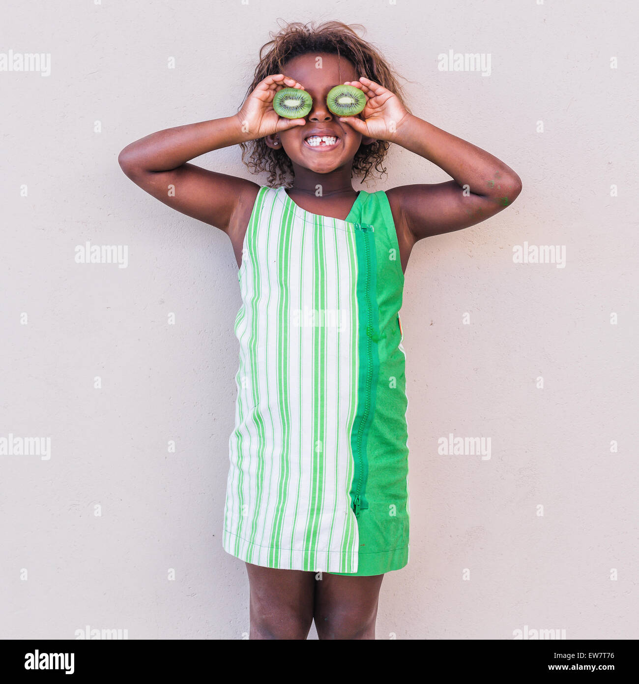 Lächelndes Mädchen im grünen Kleid Kiwis vor Augen halten Stockfoto