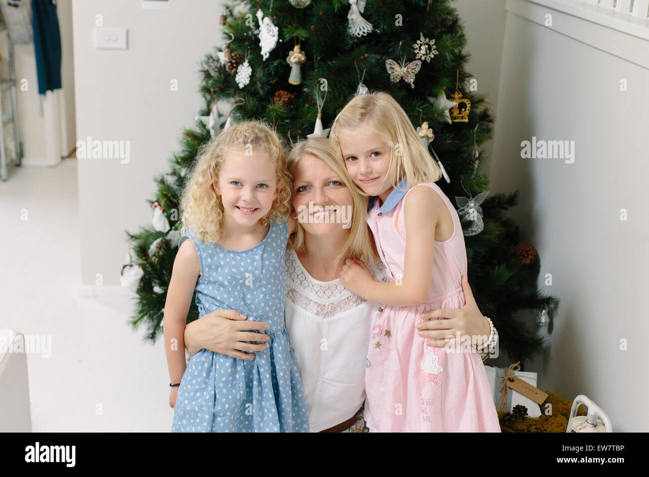 Mutter und zwei Töchter vor Weihnachtsbaum steht Stockfoto